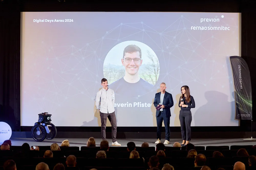 Zwei Männer und eine Frau stehen vor einer Kinoleinwand und sprechen zum Publikum im Kinosaal.