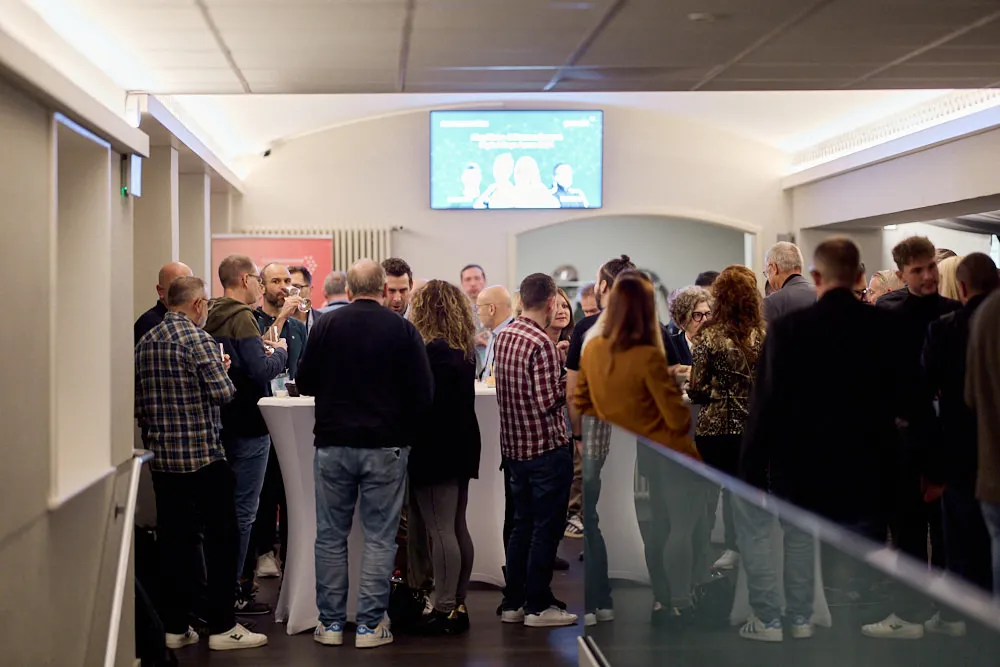 Viele Menschen stehen vor den Kinosälen an Stehtischen und sprechen miteinander.