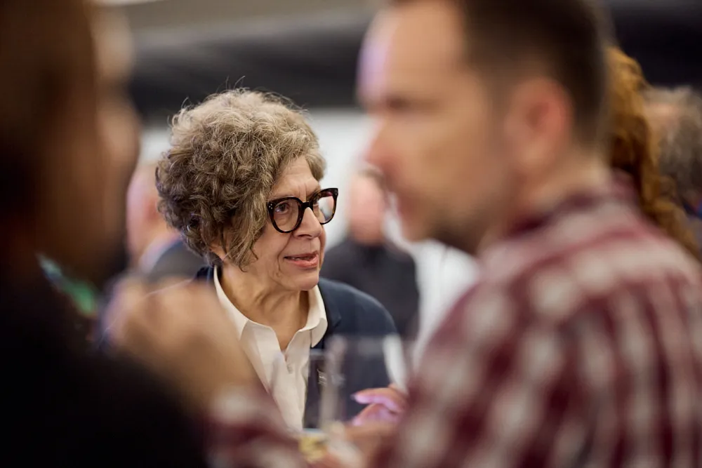 Menschen sprechen miteinander. Im Fokus ist eine Frau.