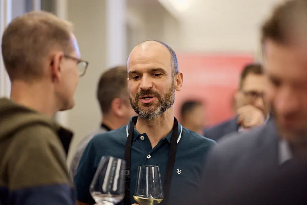 Menschen sprechen miteinander. Im Fokus sind zwei Männer, die sich unterhalten.