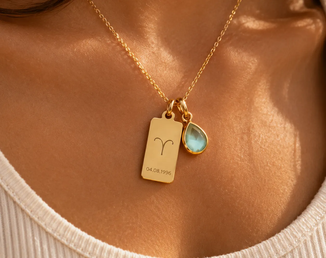 Woman wearing a personalized necklace engraved with a zodiac sign, birth date, and birthstone charm.