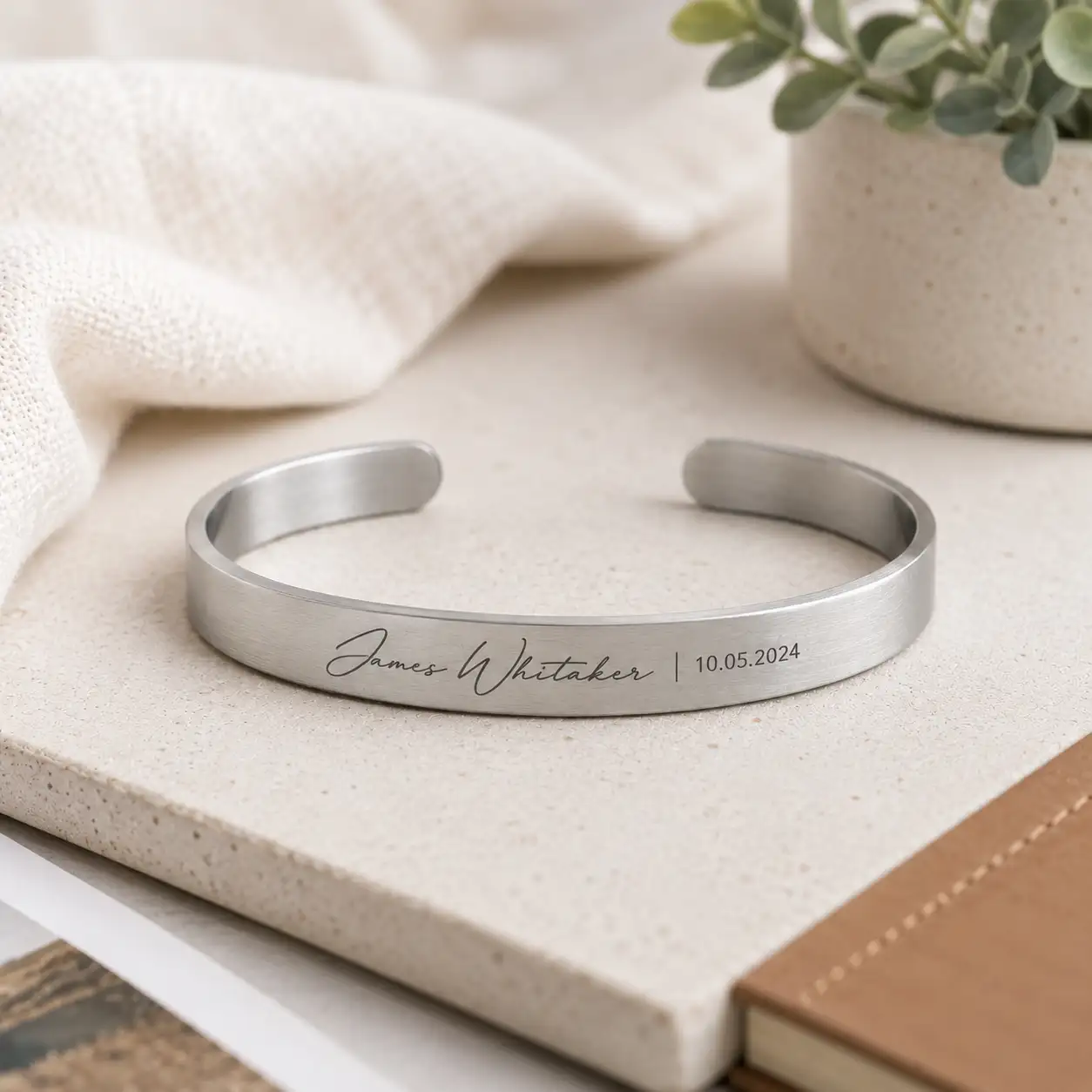 Personalized cuff bracelet engraved with a custom name and date.