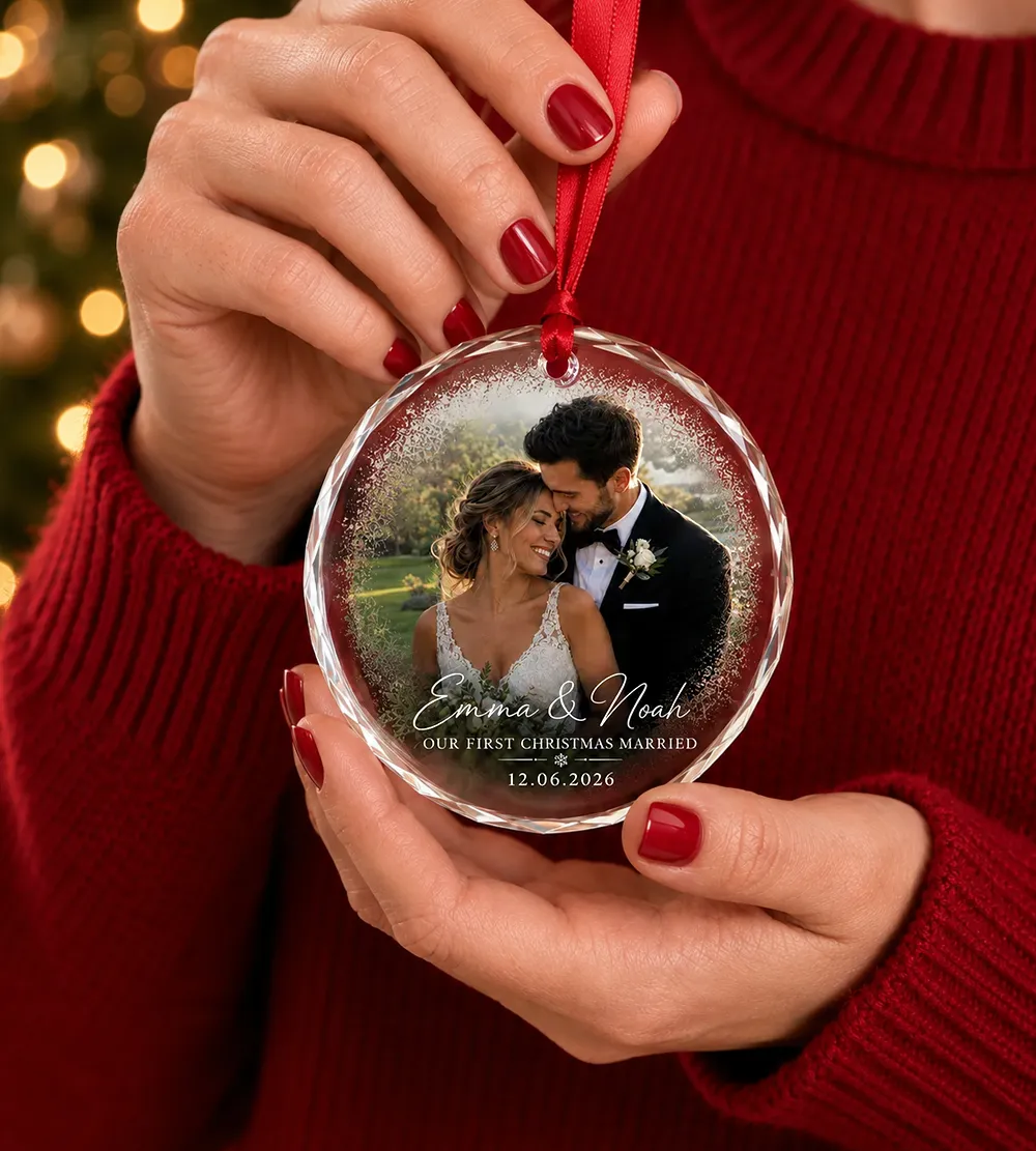 Personalized round glass photo ornament featuring a custom wedding photo, couple's names, and anniversary date.