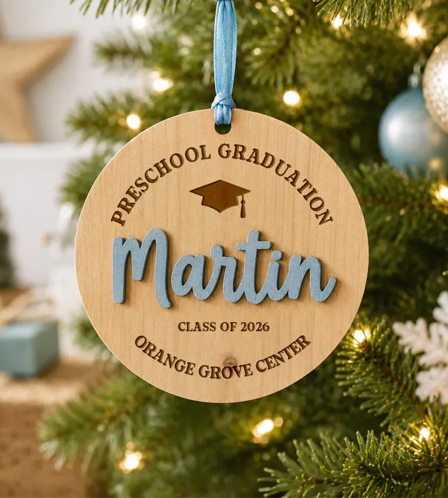 Personalized round wooden ornament with an engraved graduation design and raised custom name.
