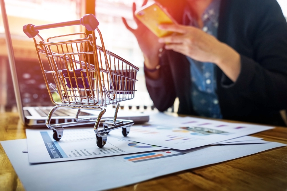 Shopping cart over papers with analytics