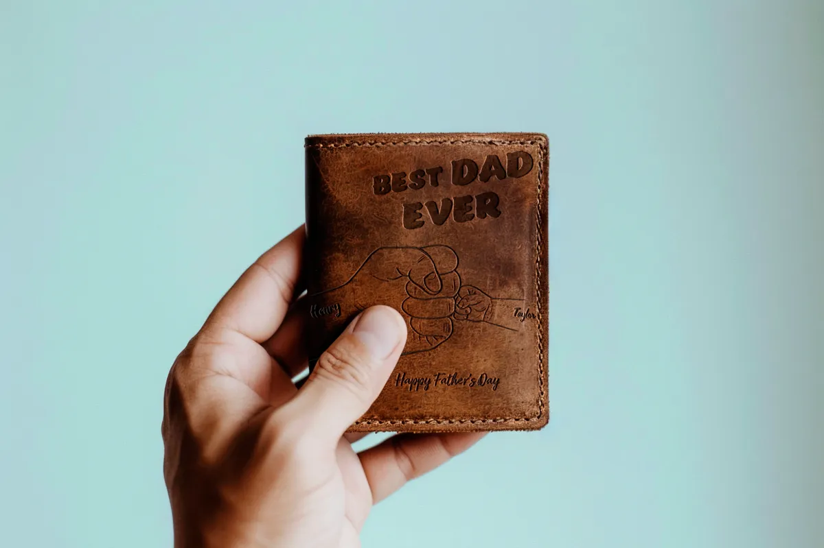 Hand holding a personalized leather wallet engraved with ‘Best Dad Ever’ and a Father’s Day message