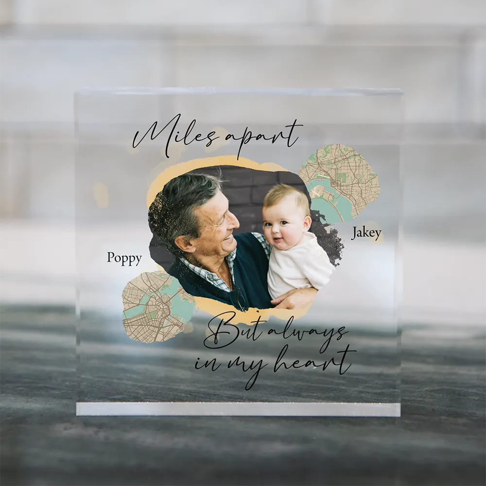Personalized acrylic square gift showing a grandparent-grandchild photo and maps connecting two locations with a heartfelt long-distance message.