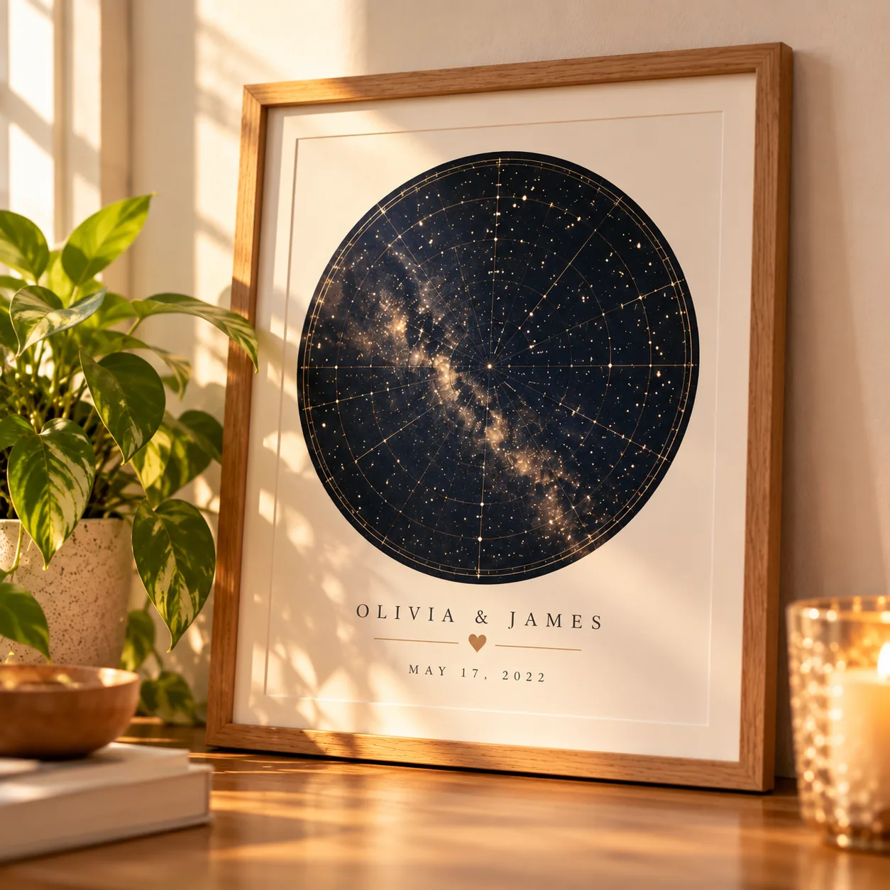 Custom-framed star map print leaning against a wall next to a small potted plant