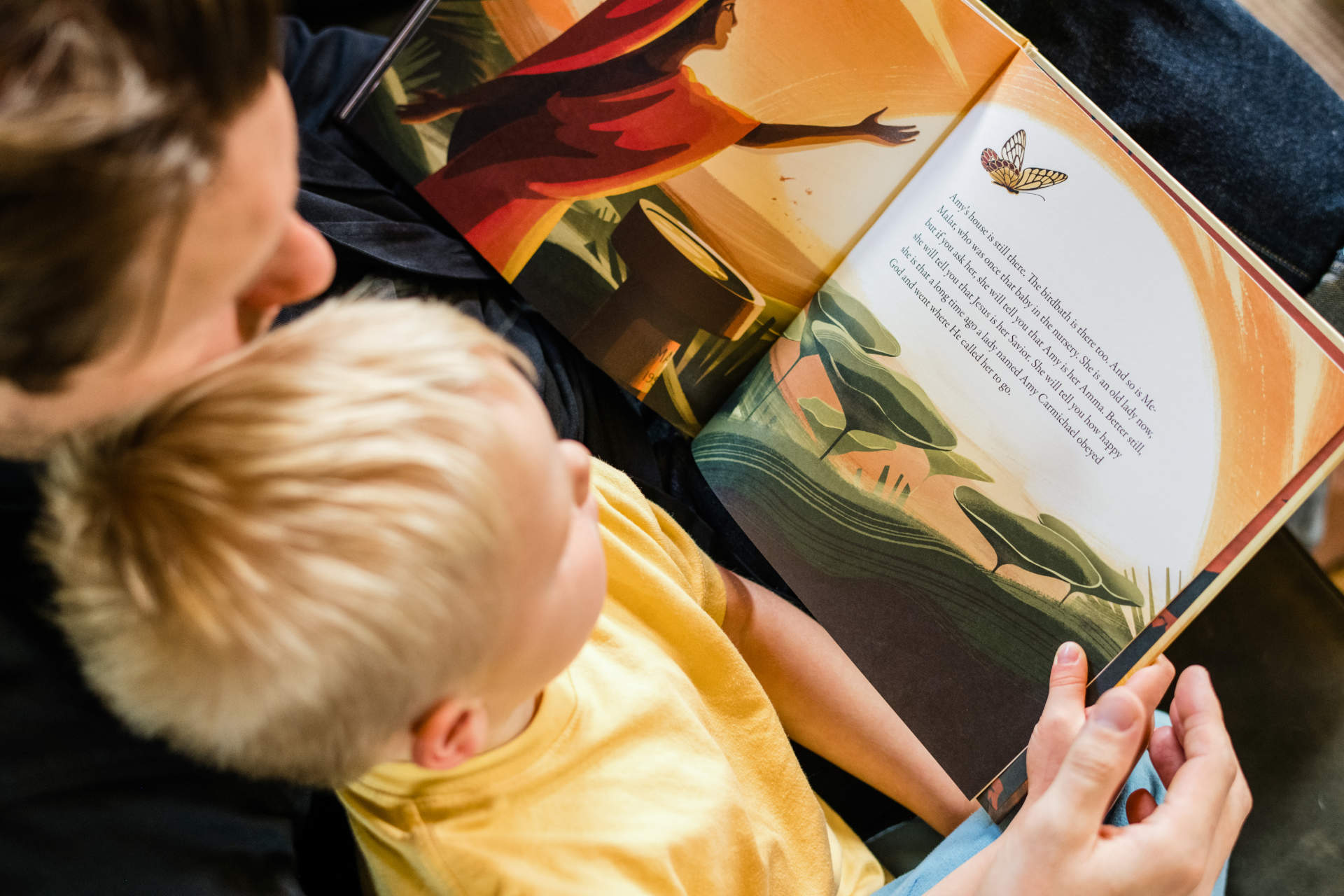 Overhead view of child on a parent's lap, reading a Goers book together
