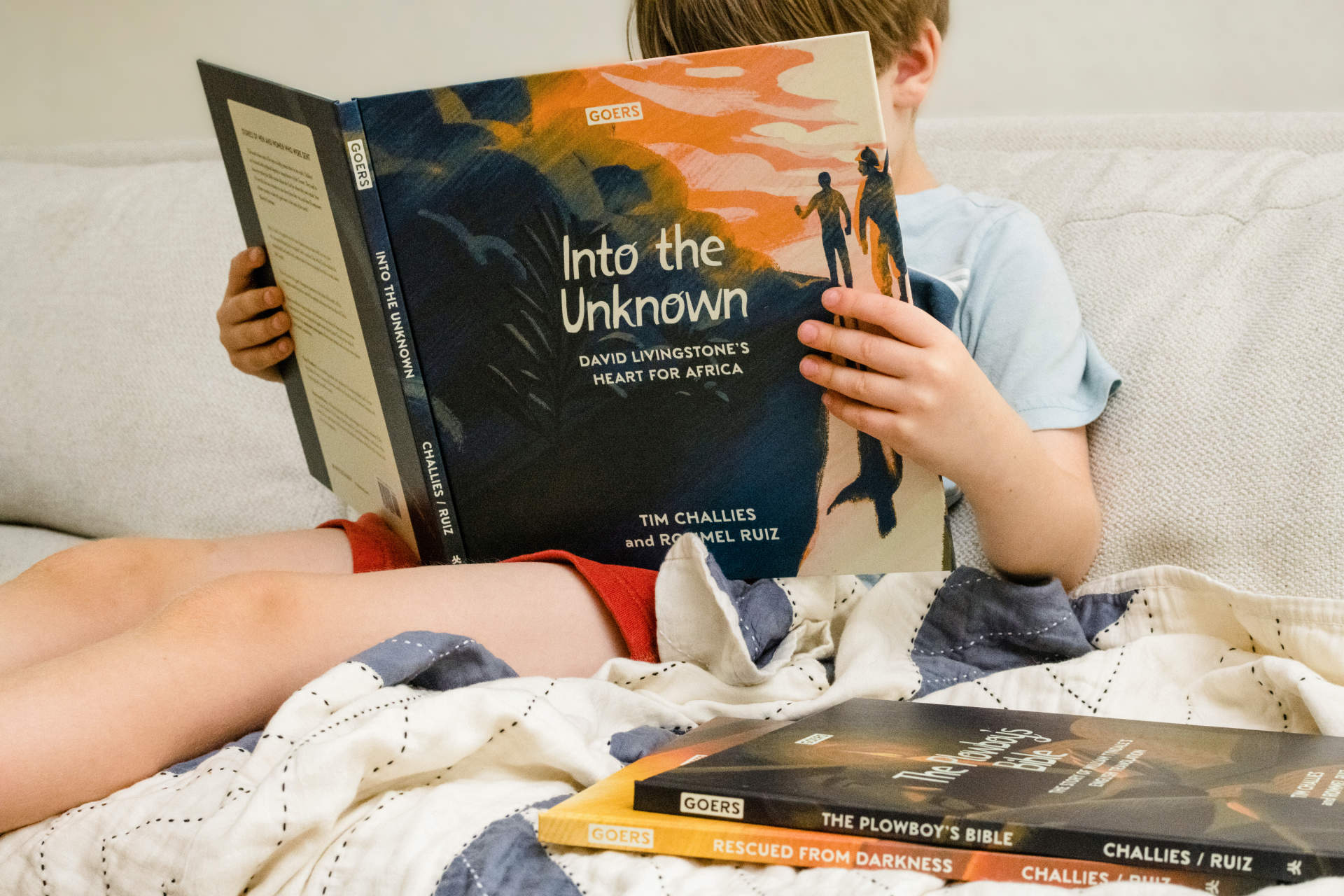 Young boy reclined and engrossed in a Goers book