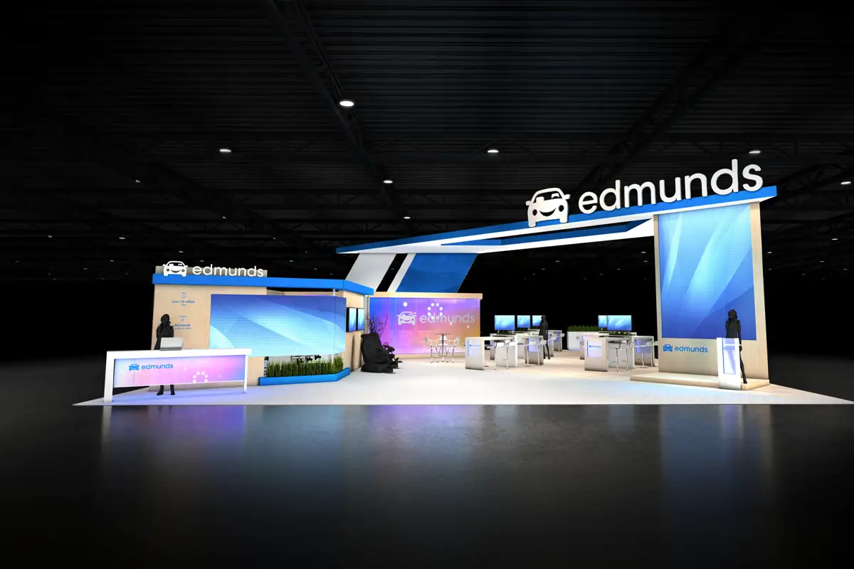 Edmunds trade show booth with digital screens, seating, and brand logos in a dark exhibition space.