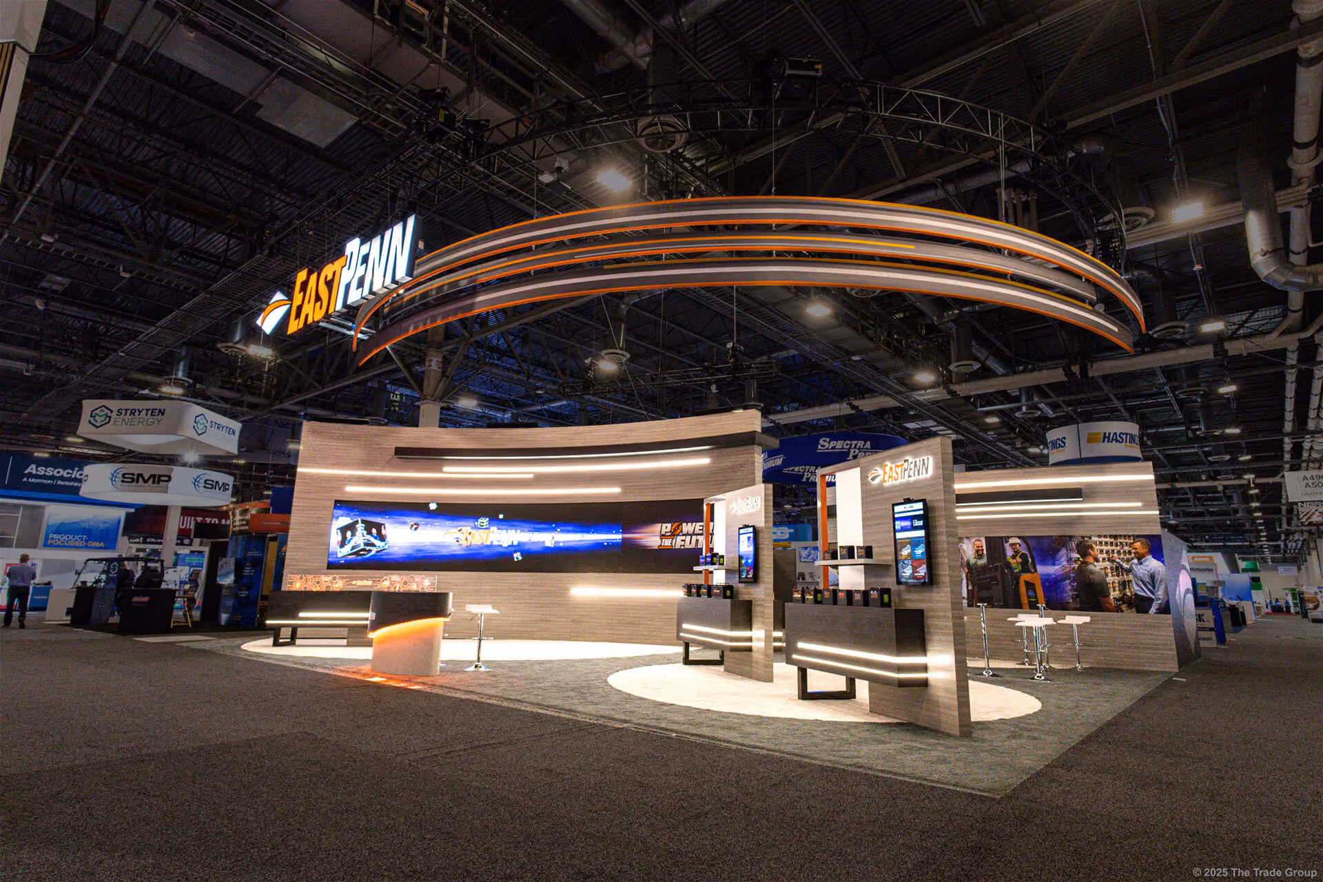 Modern EAST PENN trade show booth with curved walls, digital screens, and circular overhead signage.