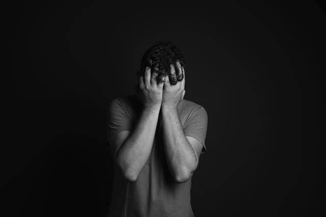 personne qui se tient la tête avec les mains en stress et burn ou 