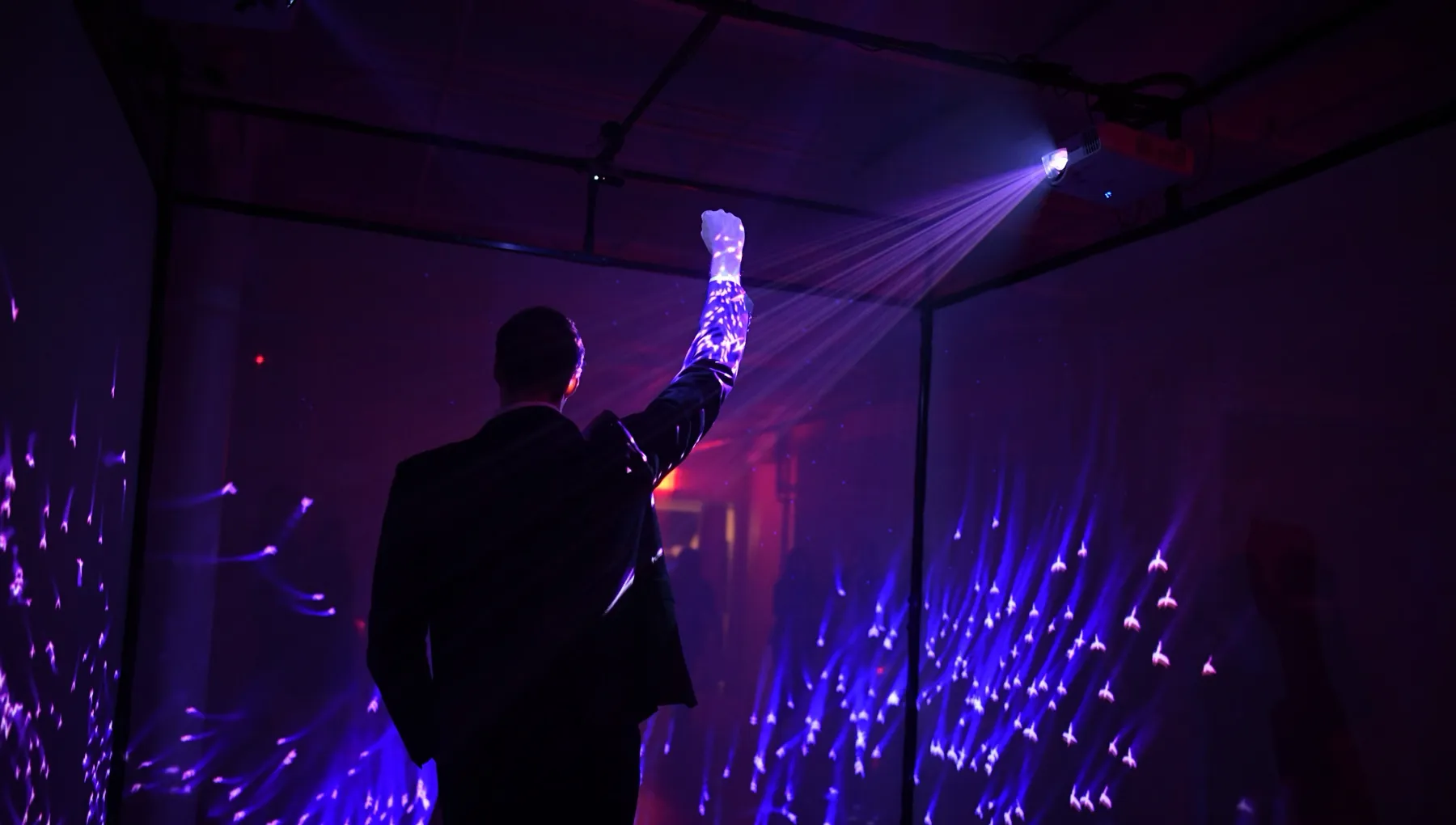 guest raising a hand inside the cube as purple light swirls around