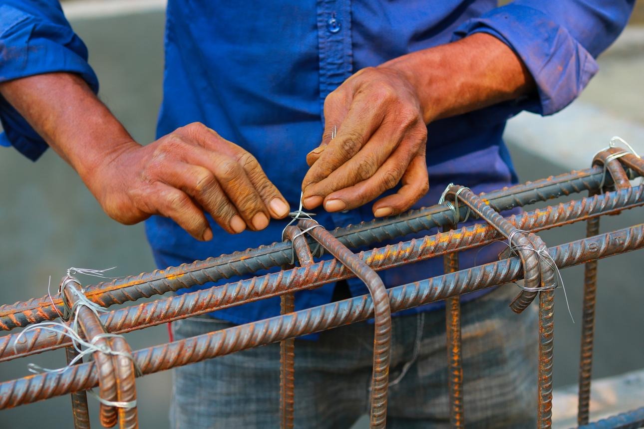 Trabajador realizando amarre de varilla con alambre recocido en obra.