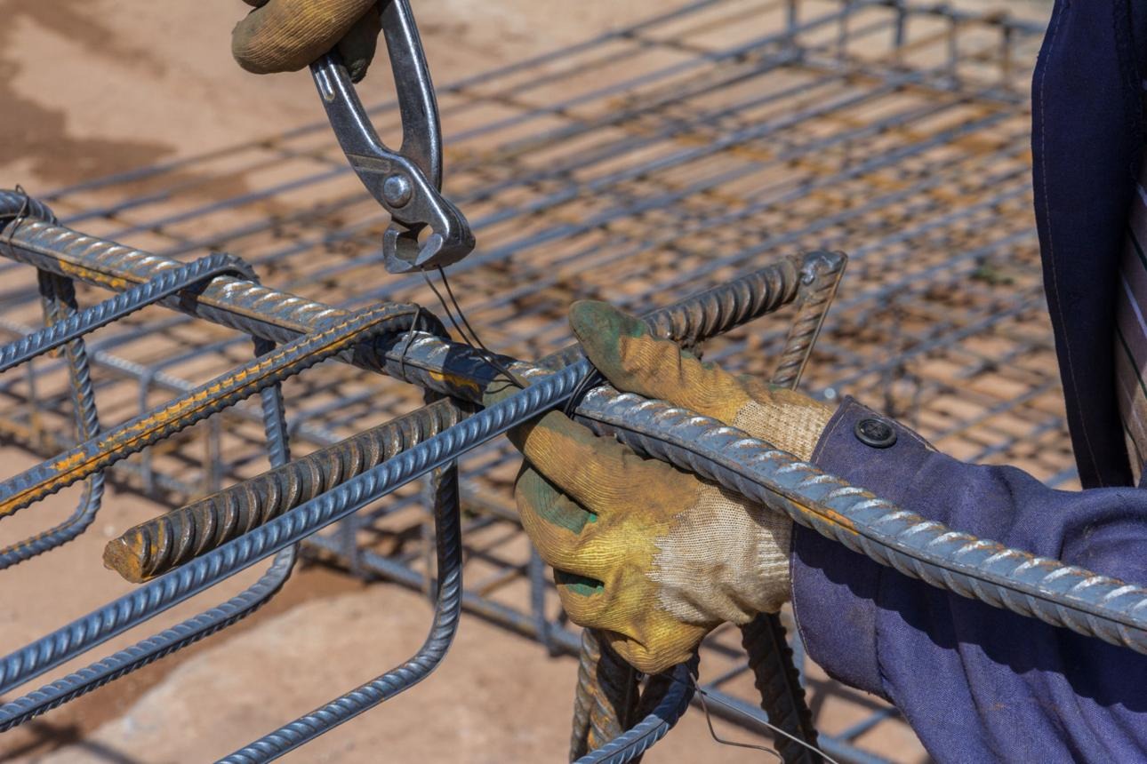 Trabajador realizando amarre de varilla con alambre recocido en obra.