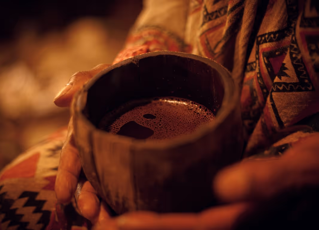 Ayahuasca cup in hand in a traditional ceremony setting.