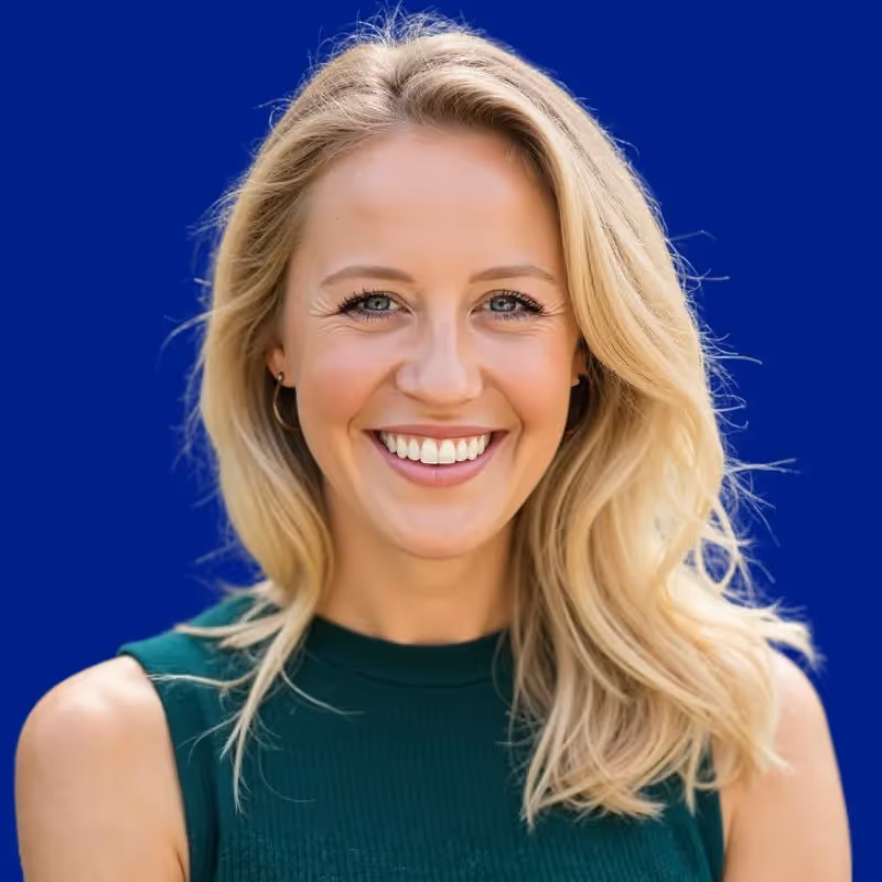 Smiling blonde woman with wavy hair wearing a sleeveless green top against a blue background.