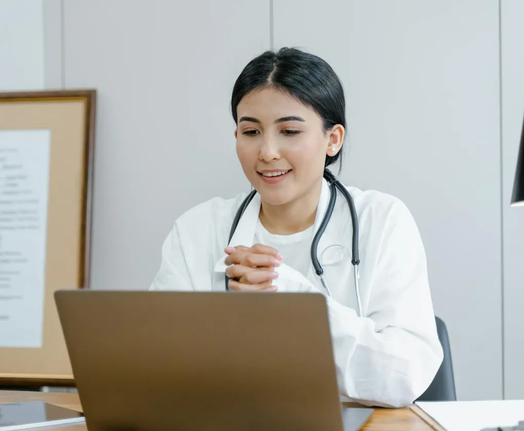 Une femme médecin consulte son ordinateur depuis son bureau.