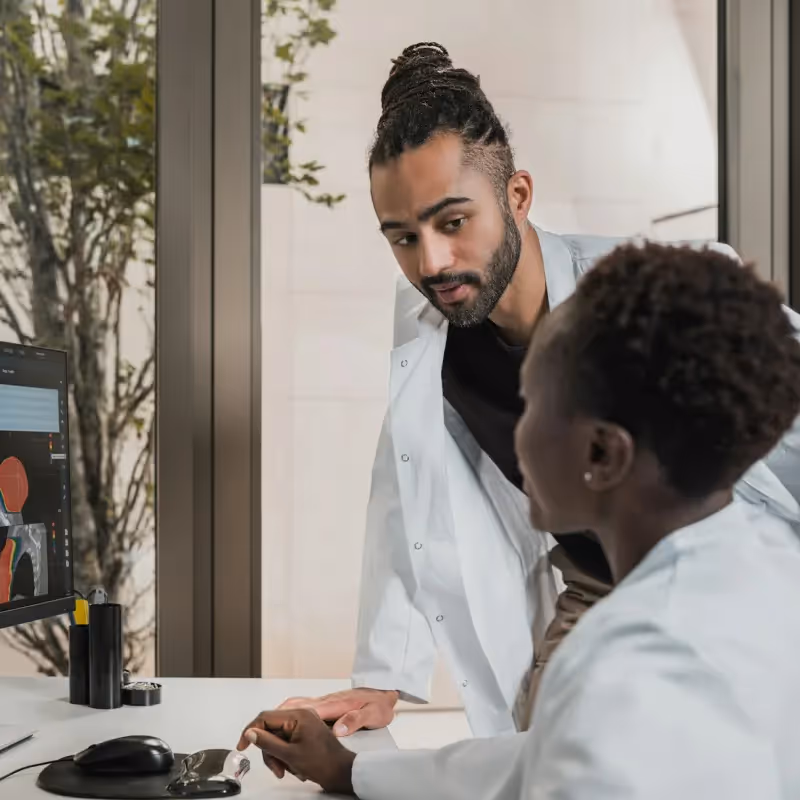 Deux médecins discutent des résultats d’imagerie d’un patient affichés sur l’écran d’un ordinateur.