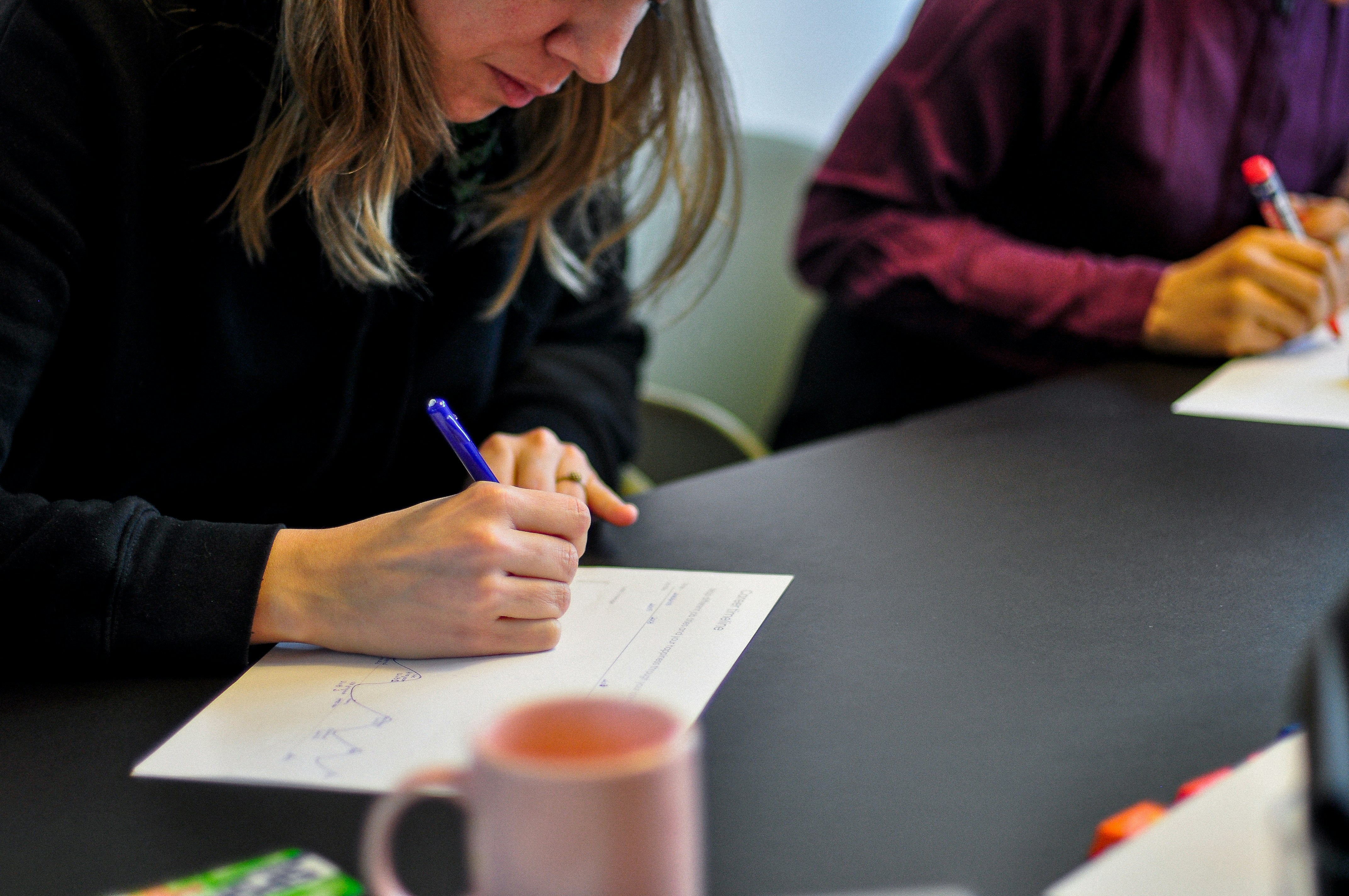 a woman writing on a paper during an AI Discovery workshop