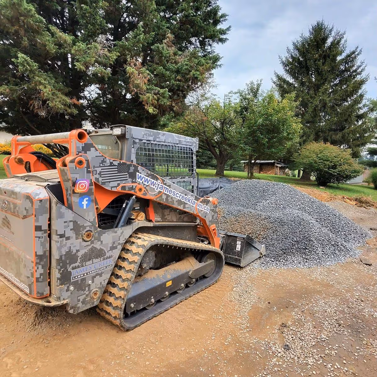 A Kubota Skid Steer machine scooping gravel by James Creek Lawn and Landscape.