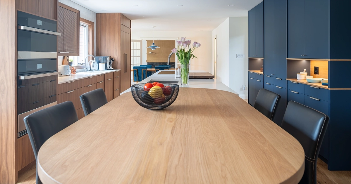 Large wooden kitchen table with wooden and painted navy blue kitchen cabinets in background