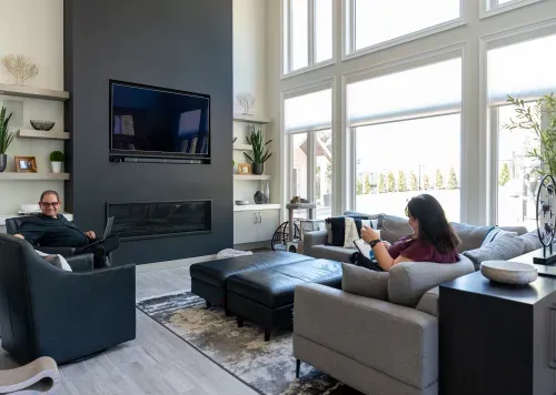 Homeowners sitting in living room with high ceilings and large windows