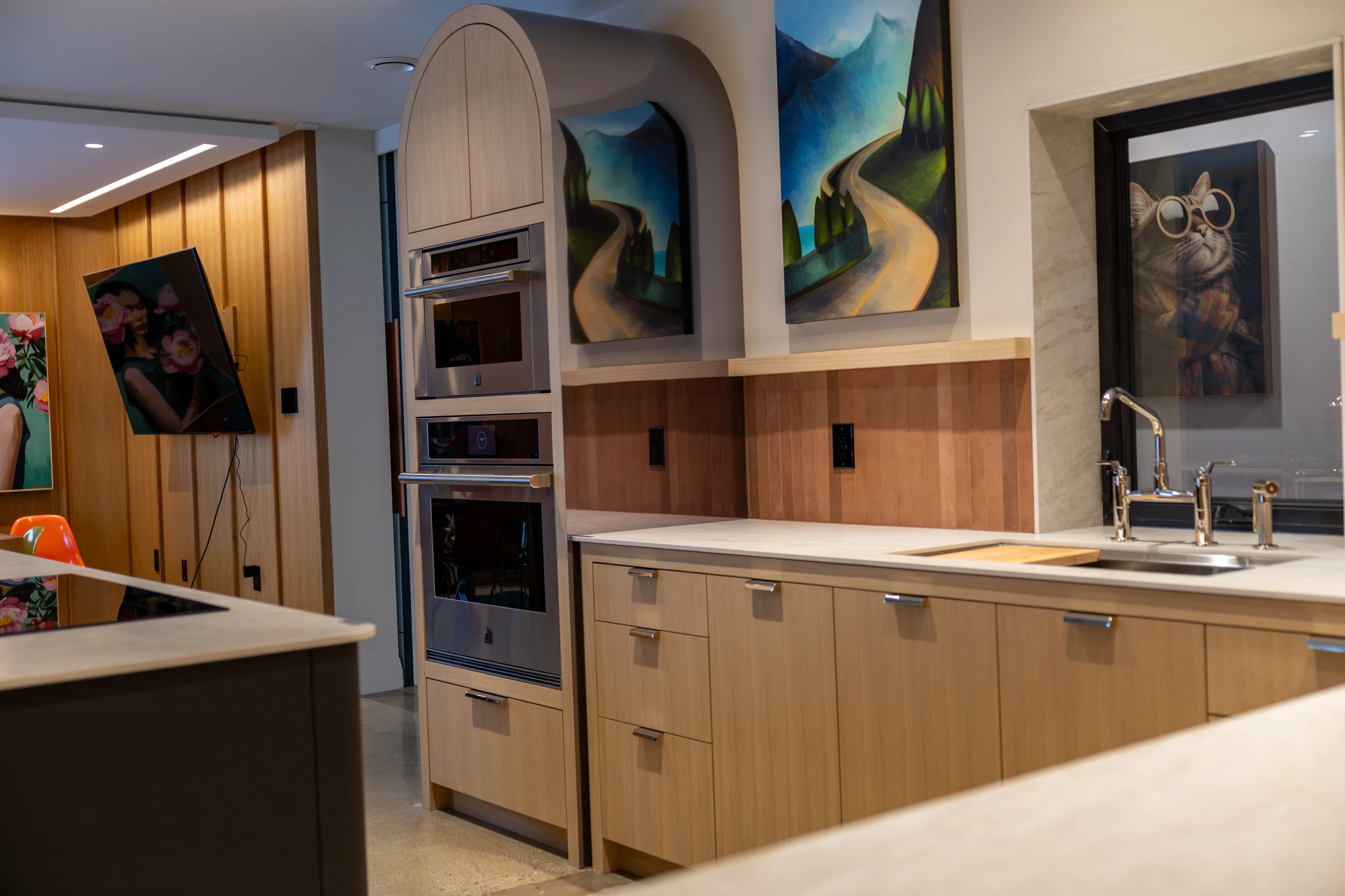 custom kitchen with light cabinets, silver faucets, paintings of pathway