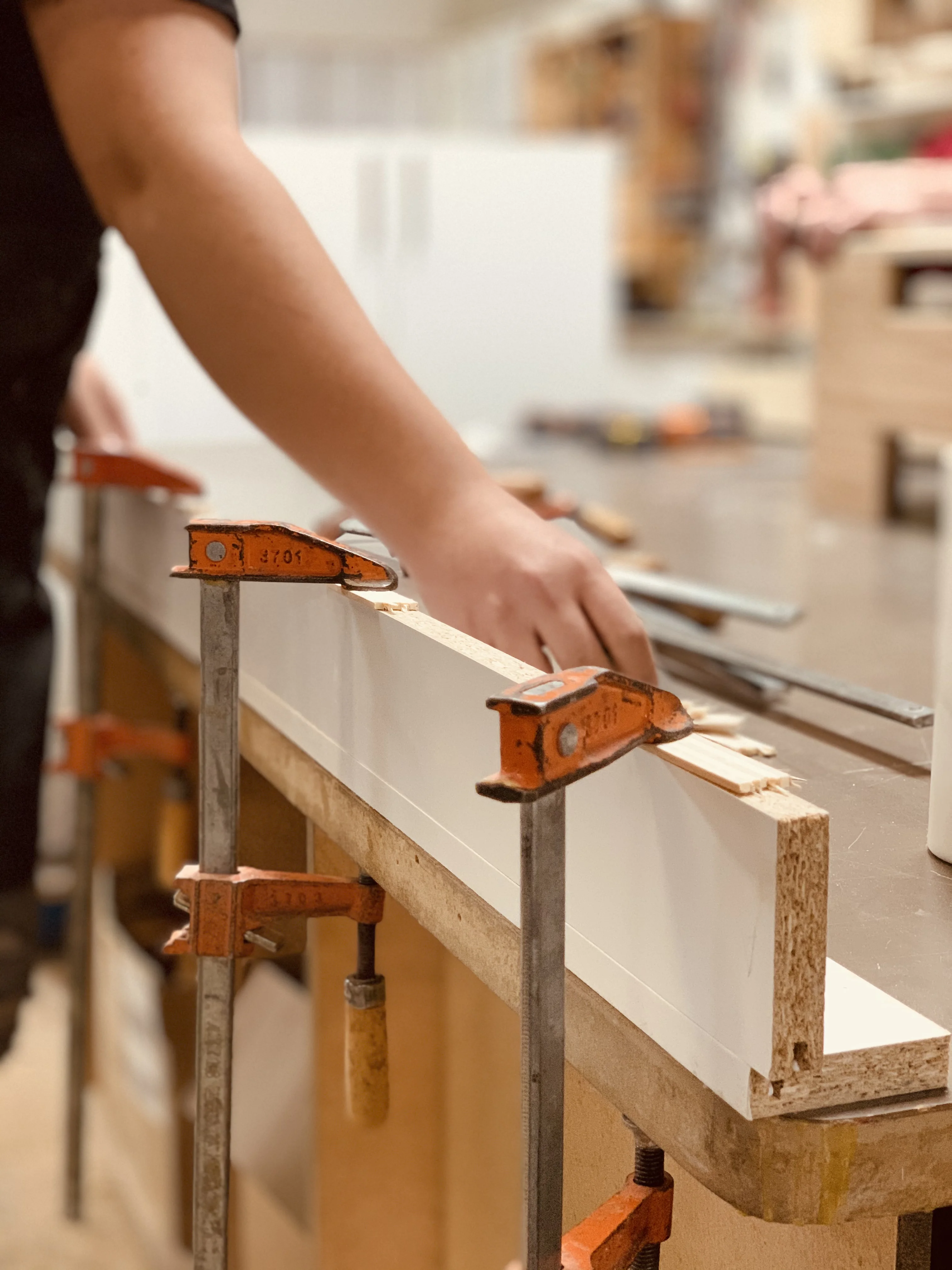 cabinet maker using clamps to hold down wood
