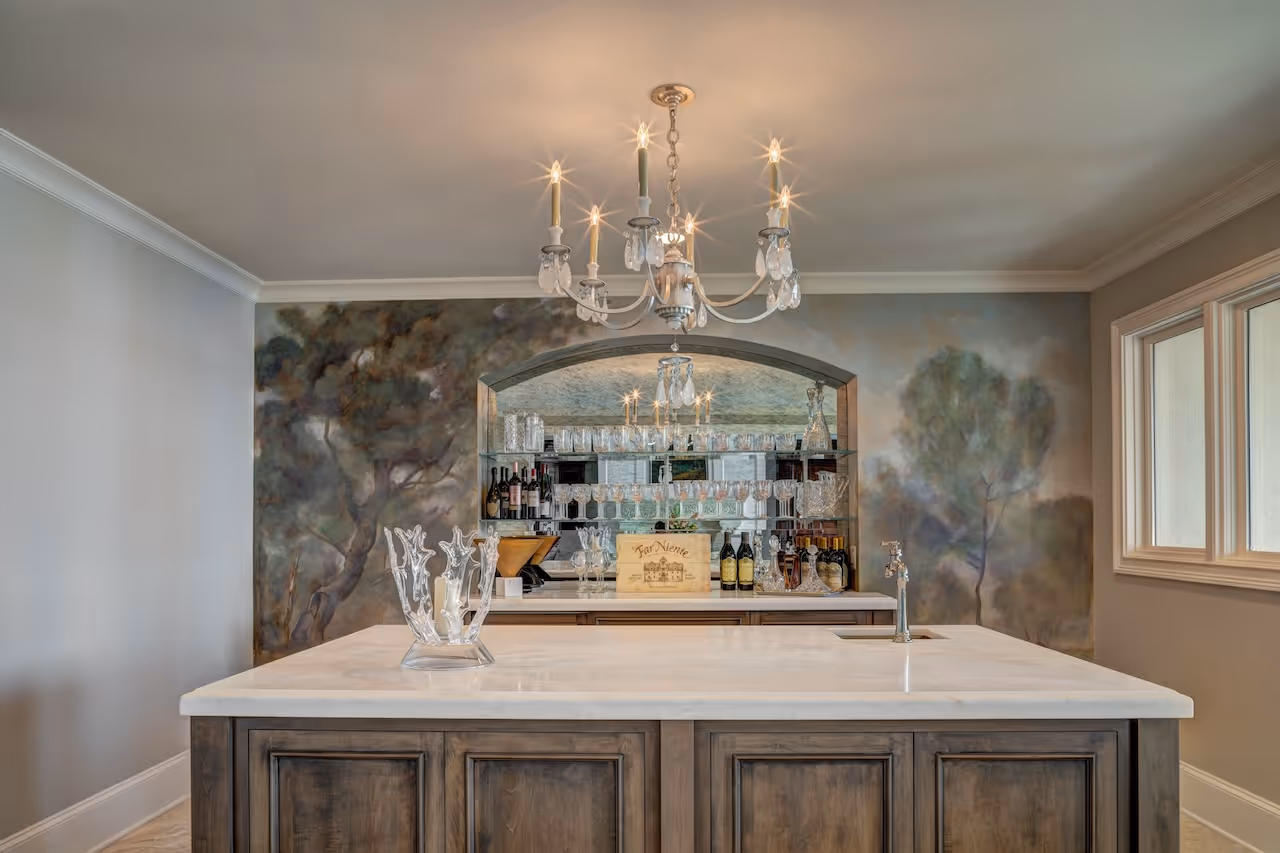 Dark wood bar with stone worktop, open shelving stocked with glassware, and built‑in fridge