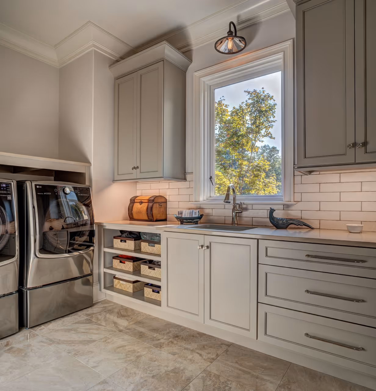 Laundry room with front‑loading washer and dryer, white cabinetry above, and marble countertop folding station