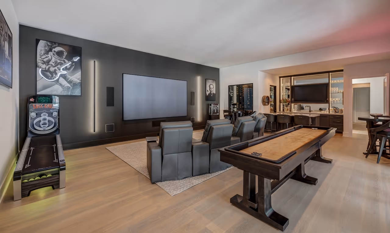 Modern theater room showcasing dark wood millwork, floor‑to‑ceiling screen, and wall‑sconce accent lighting