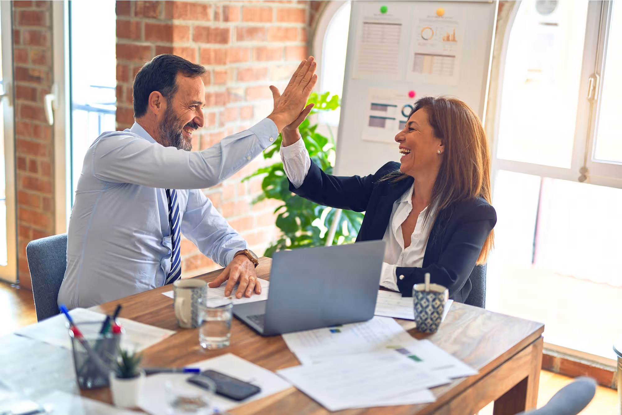 Two People High Five Each Other In Business Setting
