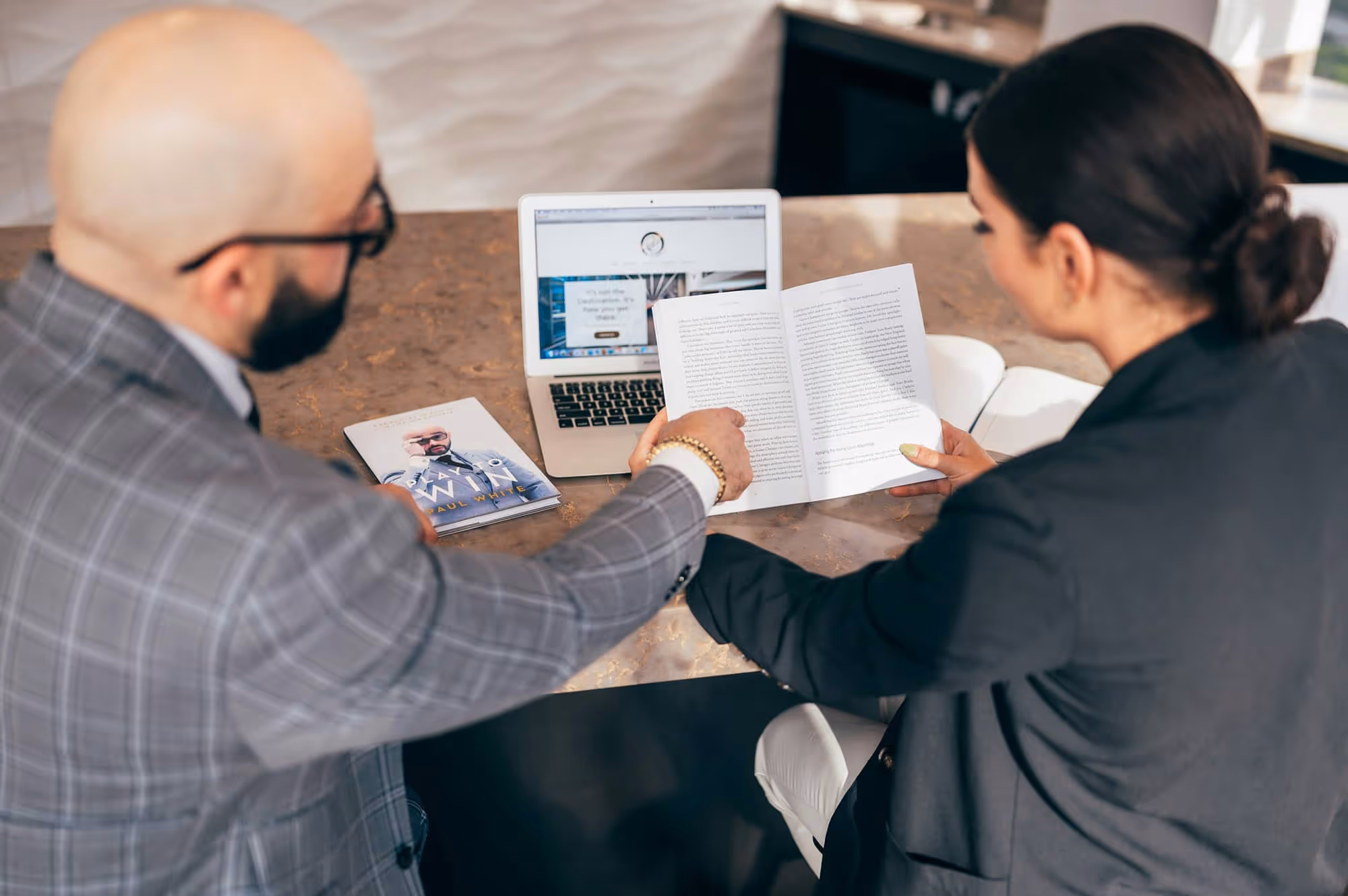 Two People Sitting Behind A Computer Discussing Business