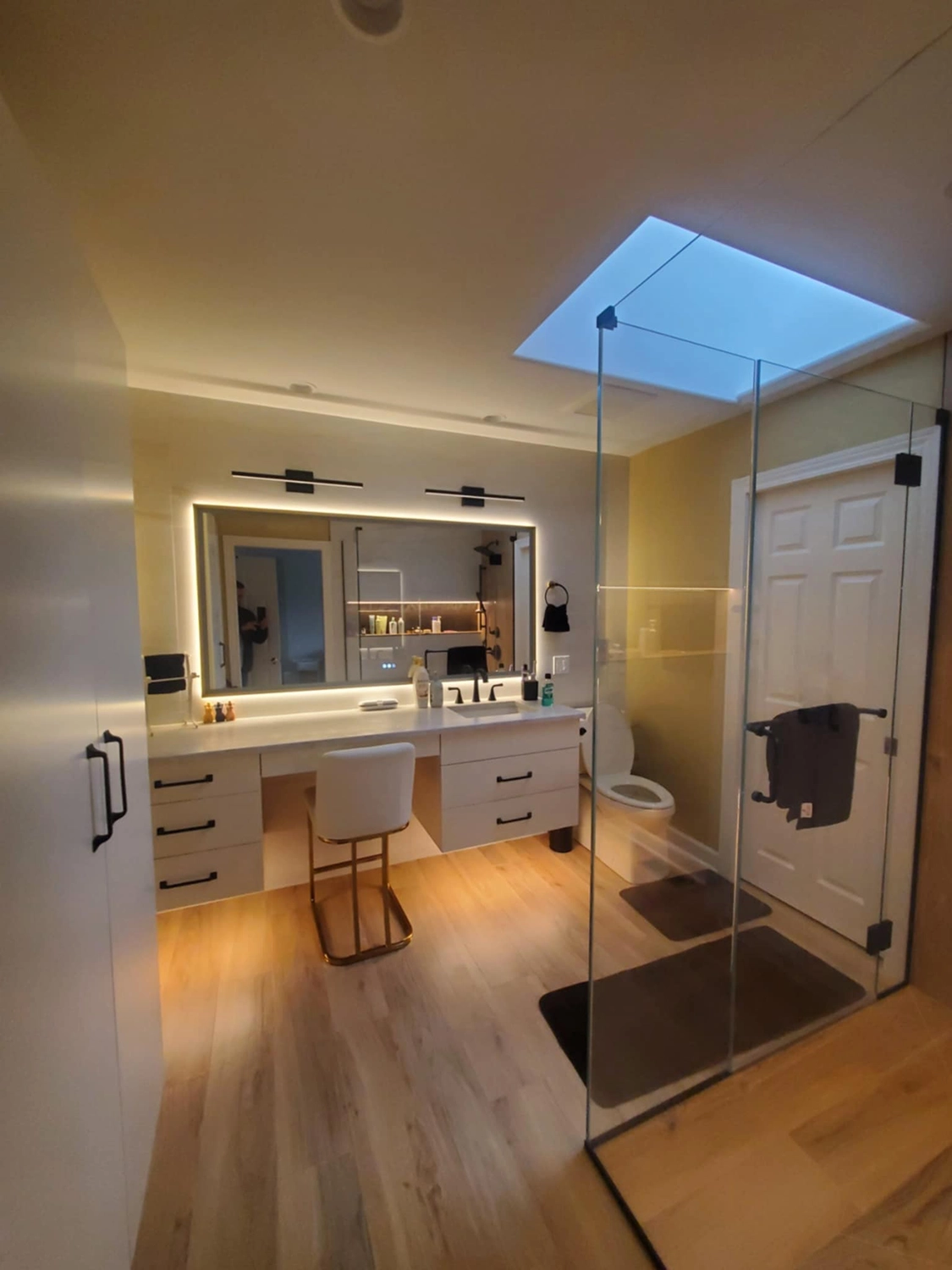 Modern White and Cream bathroom with a wooden floor and an all class shower with integrated ambient lighting