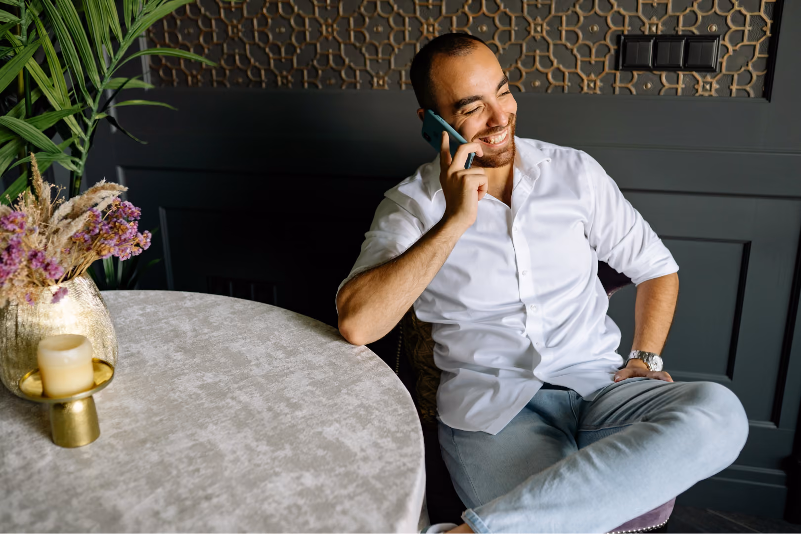 Man on cellphone call at dining room table at home smiling