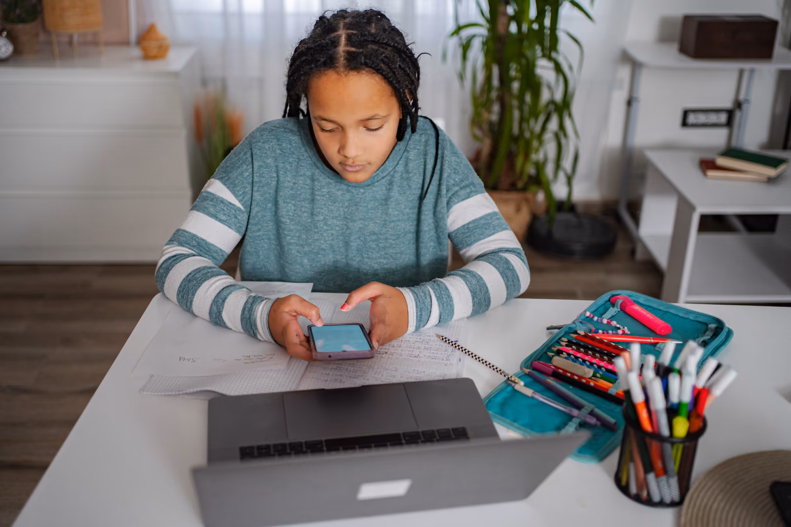 Woman distracted by phone while sitting in front of laptop.