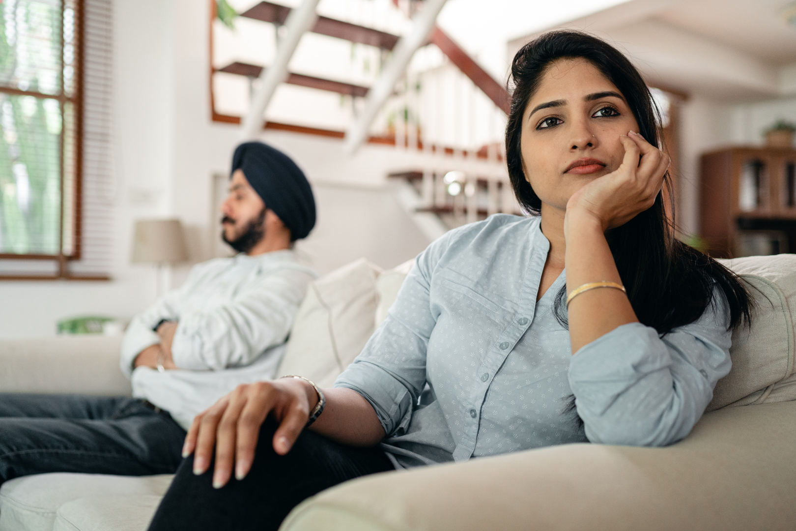 Man and woman couple sitting on couch facing away from eahcother.
