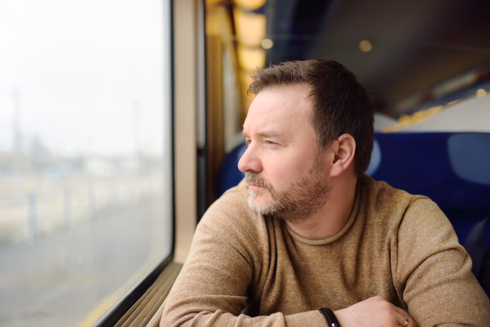 Man sitting on train looking out the window pensively