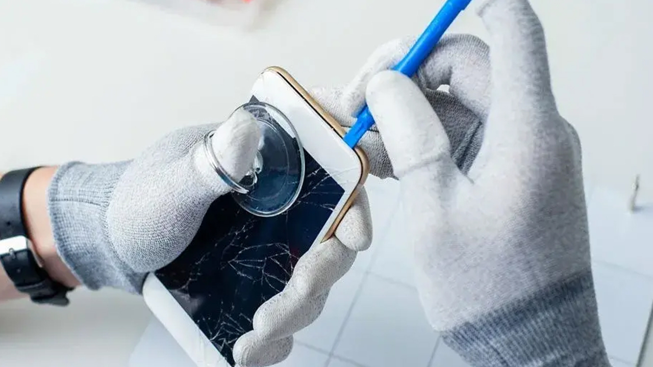 Technician in gloves repairing a cracked phone screen