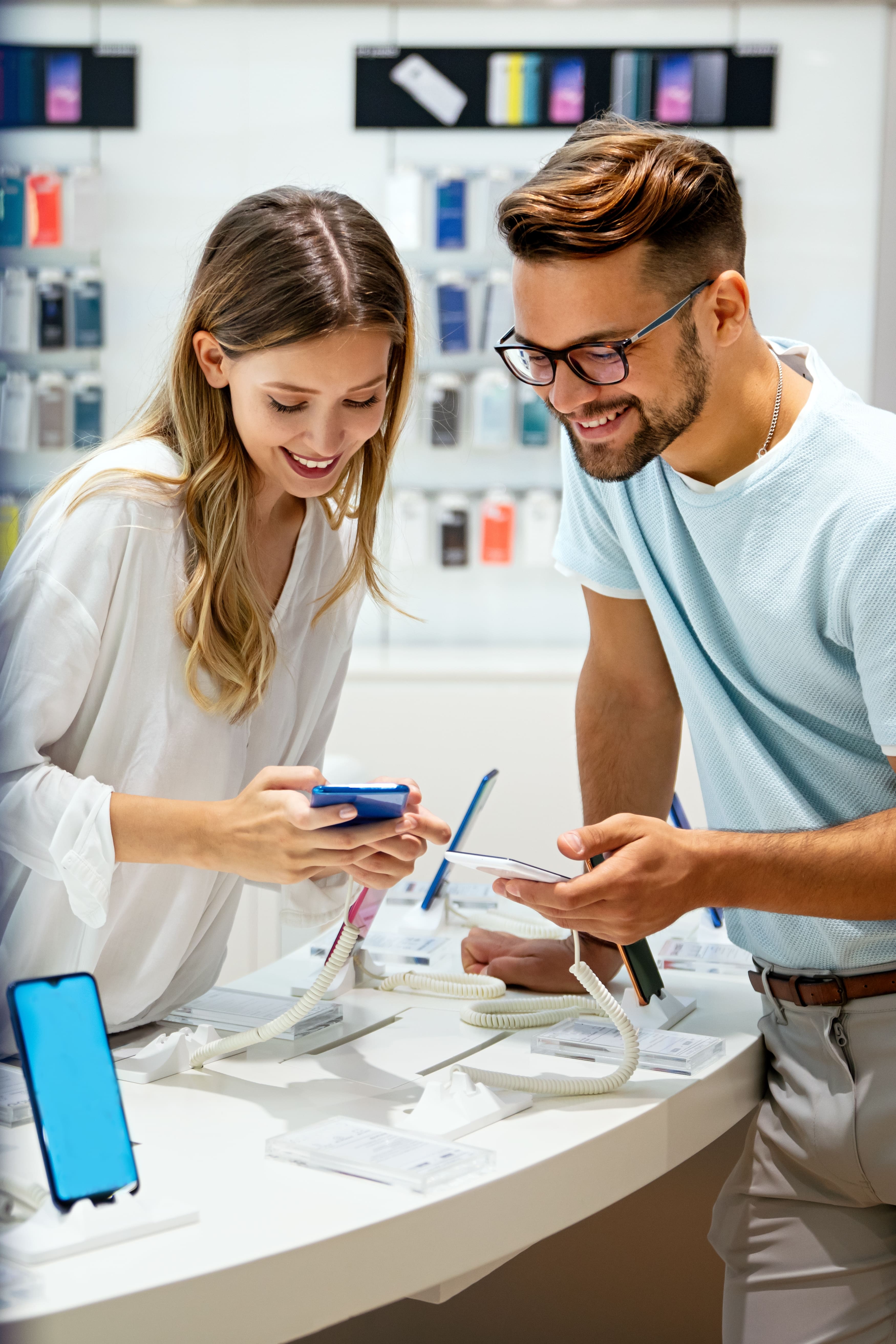 Two customers looking at smartphones in a phone shop