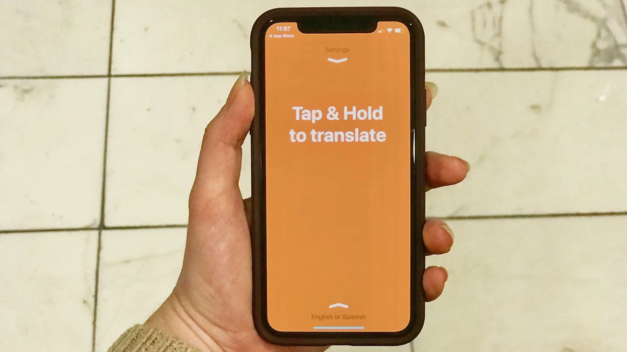 Hand holding a phone running a translation app with a Tap & Hold to translate button