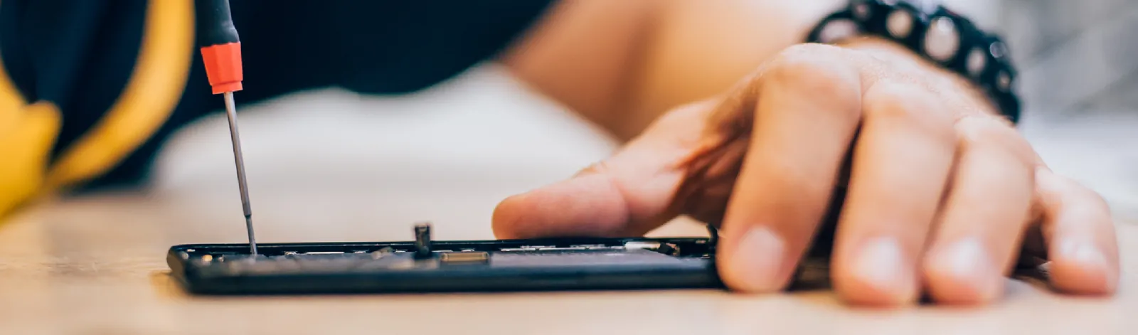 Technician repairing a phone with a screwdriver