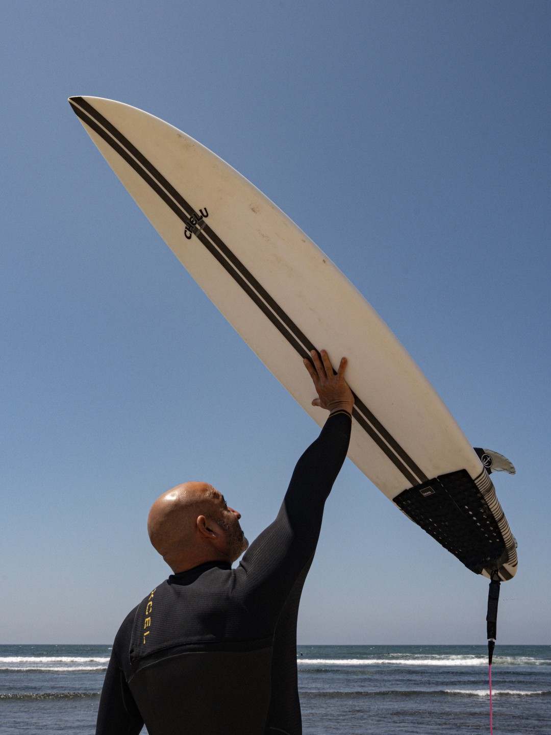 Surfer holding handcrafted Chelu surfboard at the beach – surf lifestyle photography