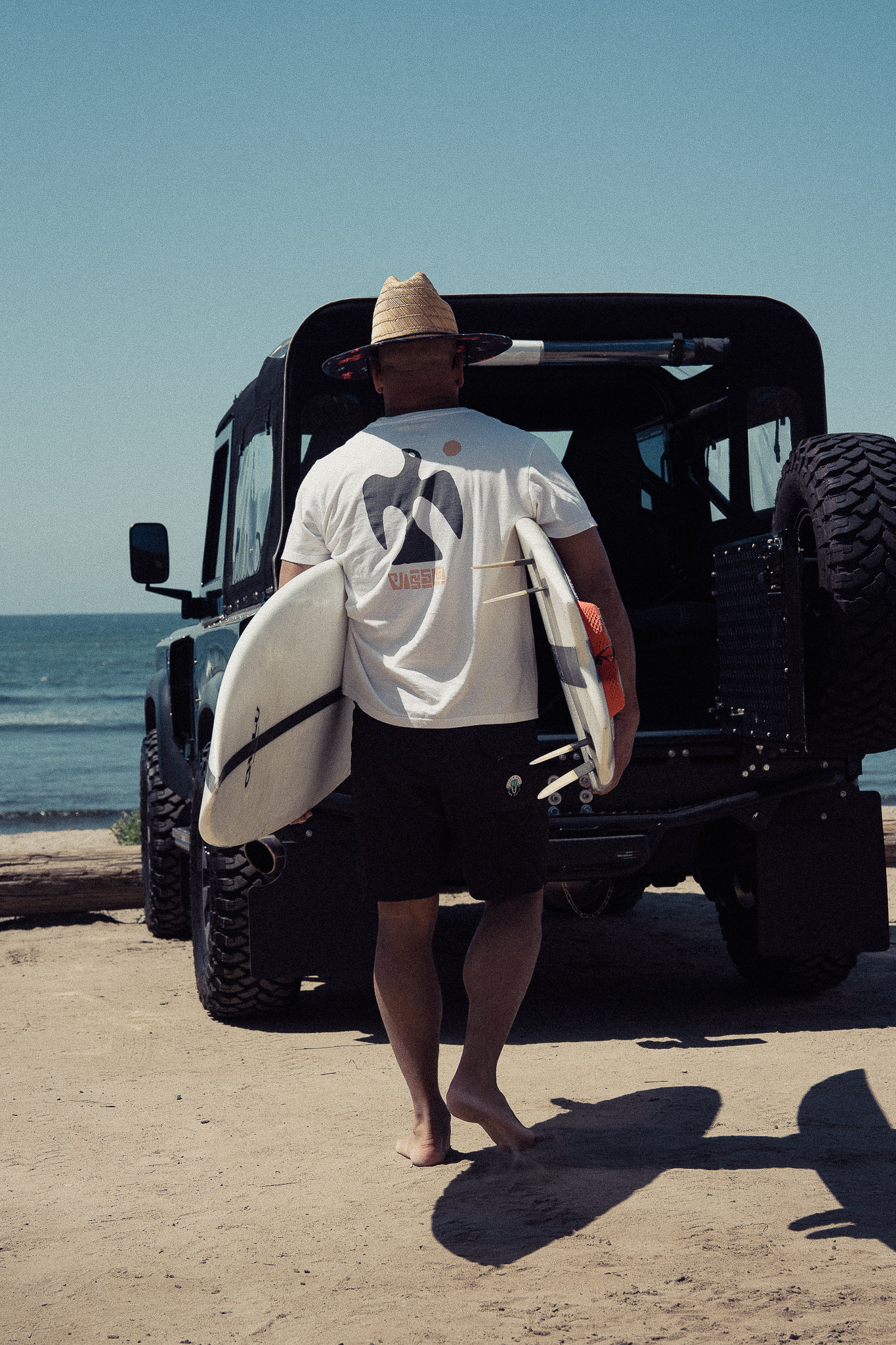 Surfer carrying handcrafted Chelu surfboards toward the beach – surf lifestyle photography