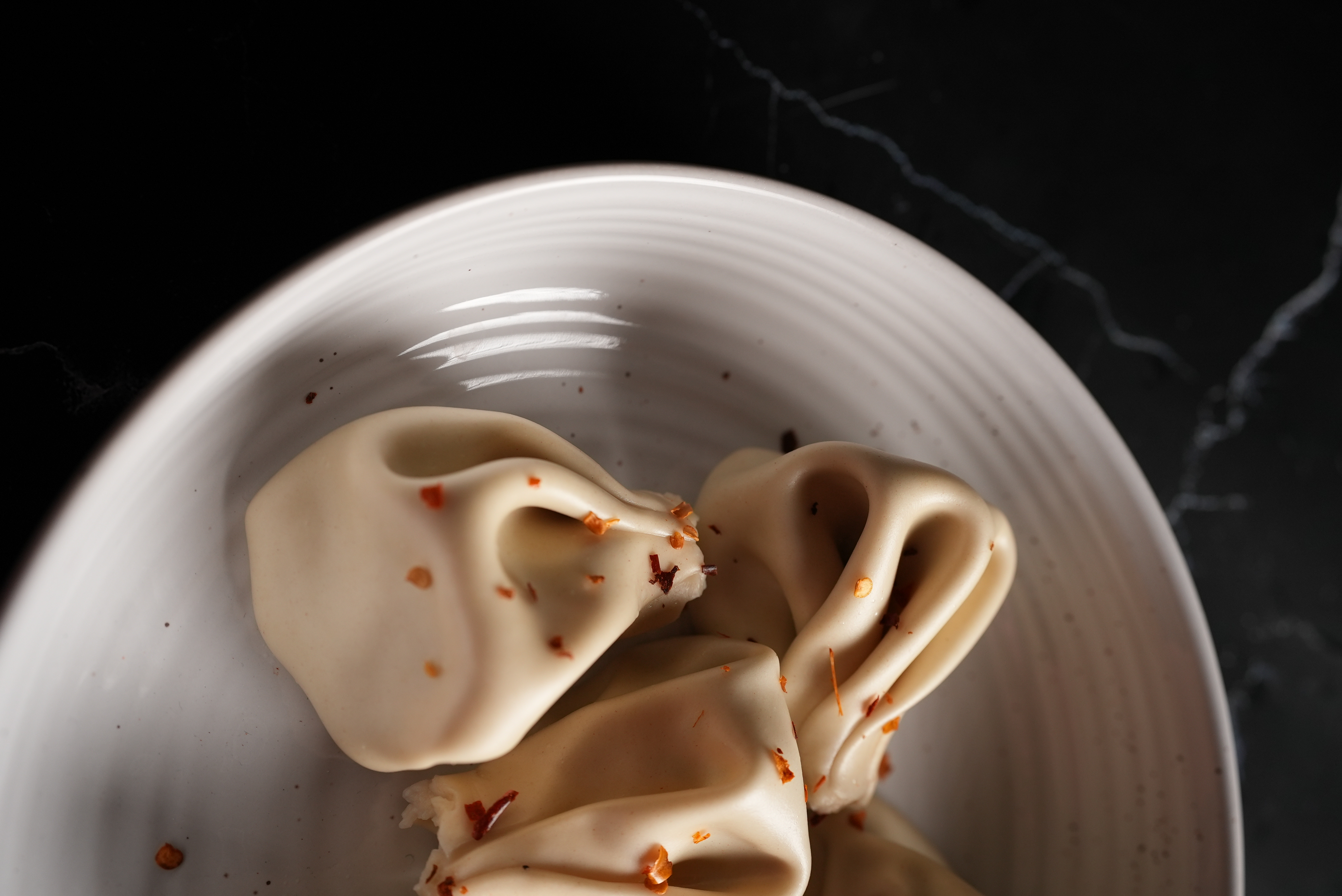 Boiled khinkali dumplings served on a wooden dish.