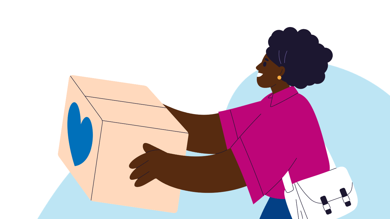 Person with curly hair and pink shirt smiling while holding a box with a blue heart on it.
