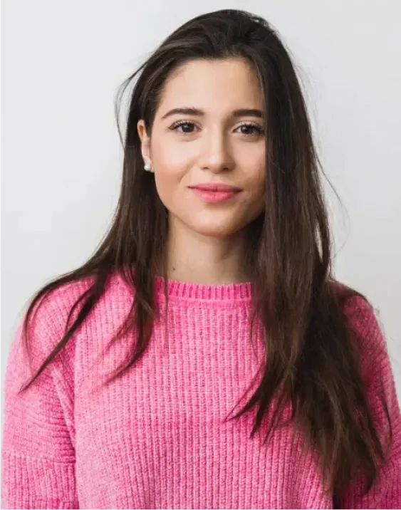 A woman with long hair wearing a pink sweater.