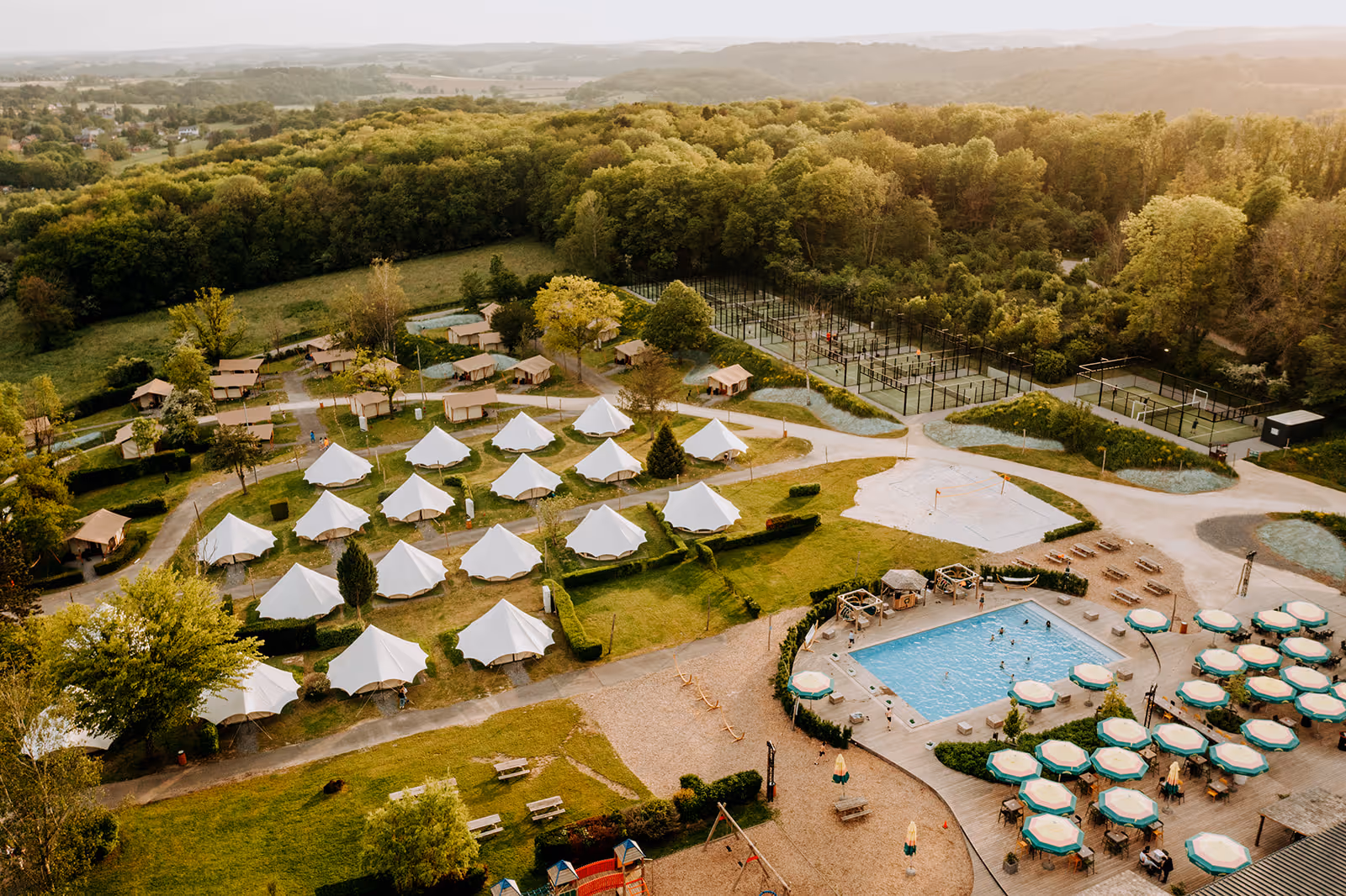 Le camp de vacances Greenfields, avec des tentes haut de gamme, de la verdure et une piscine.